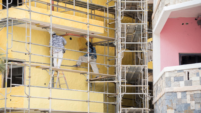 足場を使った塗装工事現場で働く職人